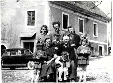 Zadaj Pavla, Janko, teta Ivanka spredaj Marinka, nona Ivana, Janko , nono Jernej, Malči in Anica, manjka Emiljan, pred domačo hišo ok.1960